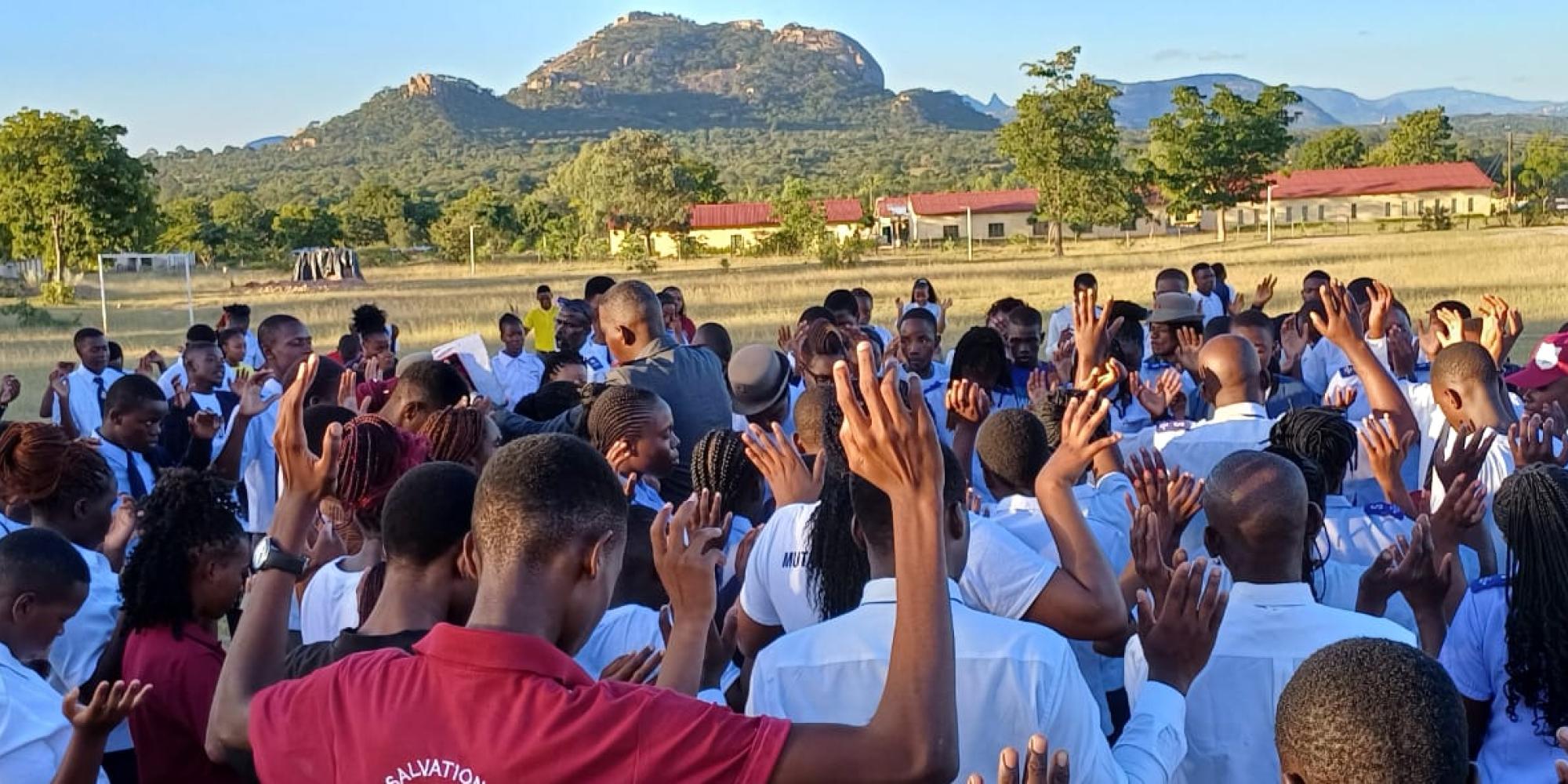A crowd of people raise their hands in prayer