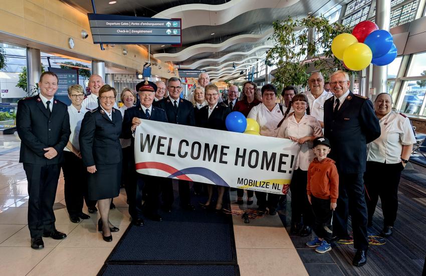 A group of Salvationists holding a banner reading 'welcome home!'